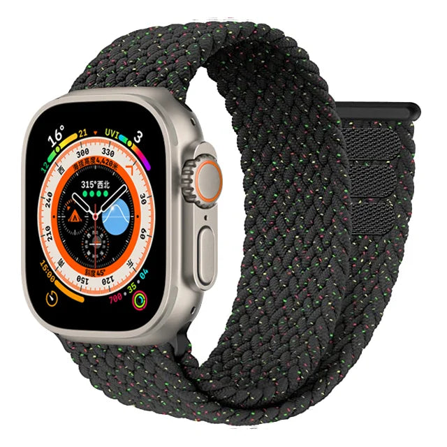 A close-up image of the Apple Watch Adjustable Loop Band. The band features a sleek, continuous loop design made of stretchable woven material that creates a comfortable, snug fit against the wrist. The innovative pull tab mechanism allows for precise size adjustment without buckles or clasps. The band's textured fabric displays fine diagonal weave patterns and appears in the signature Apple minimalist aesthetic. The end of the band connects seamlessly to the Apple Watch housing, emphasizing the clean, unin